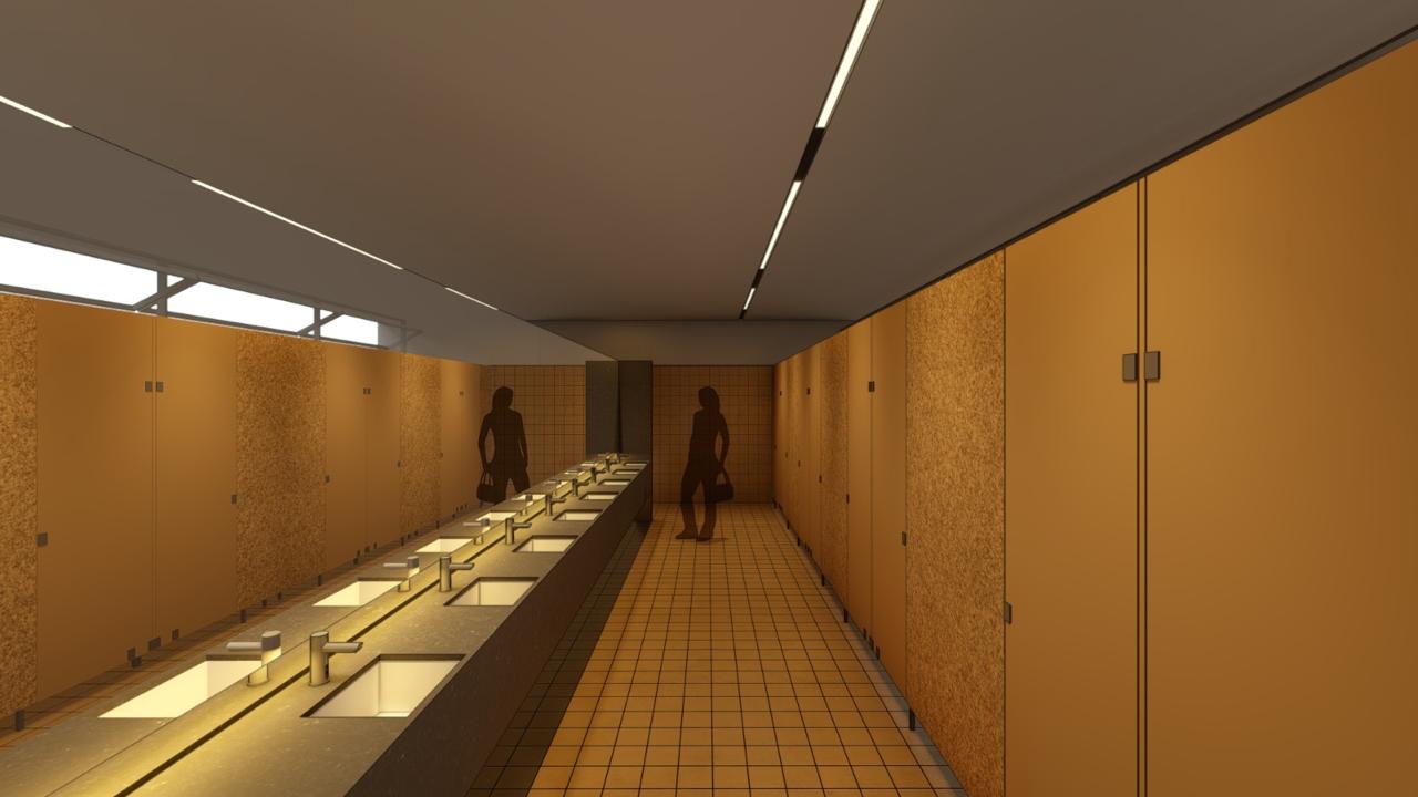 Corredor de banheiros com bancada de lavatórios iluminada e cabines